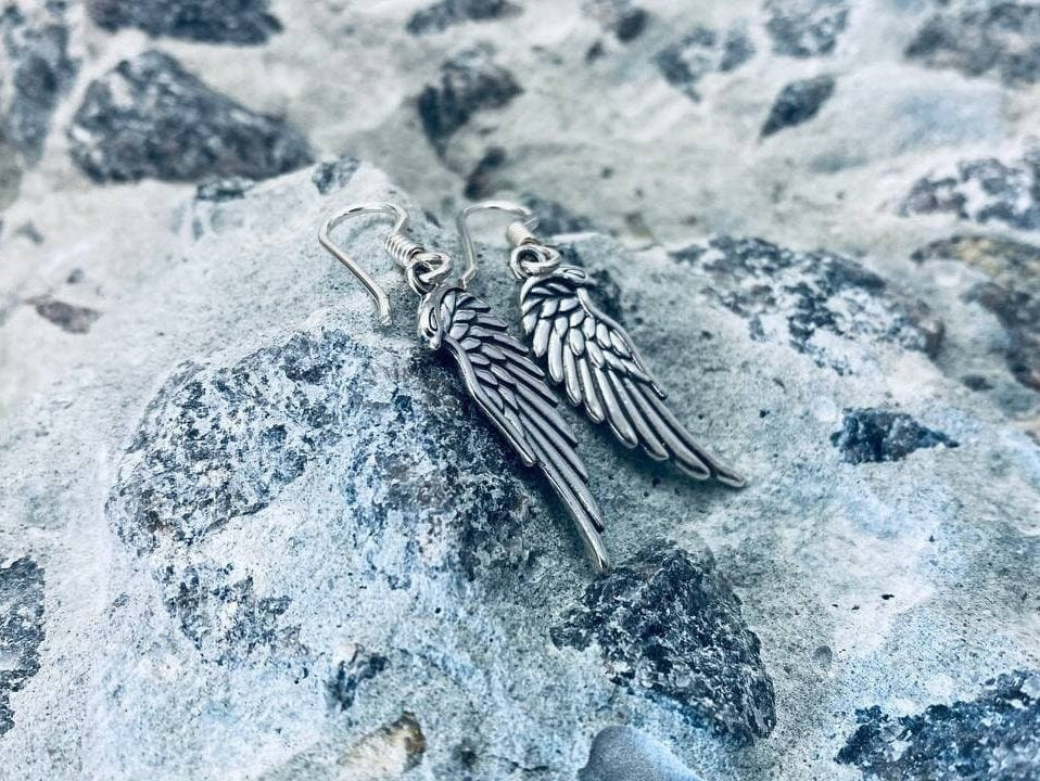 Pair of oxidized silver angel wing earrings with layered feather detail on stone