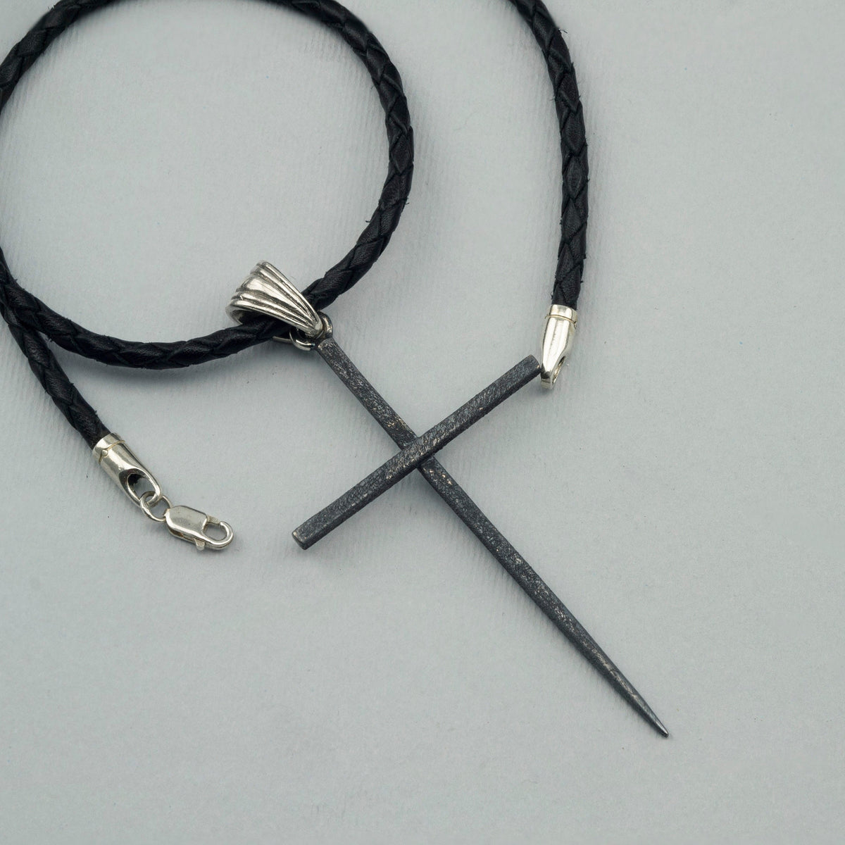 Black Spike oxidized sterling silver cross pendant with ribbed bail on a black braided leather cord
