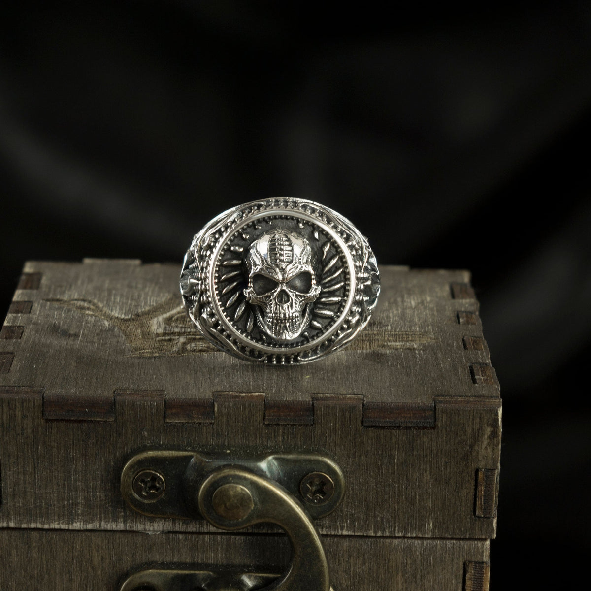 Blade Boss heavy sterling silver skull ring with circular relief on a wooden box