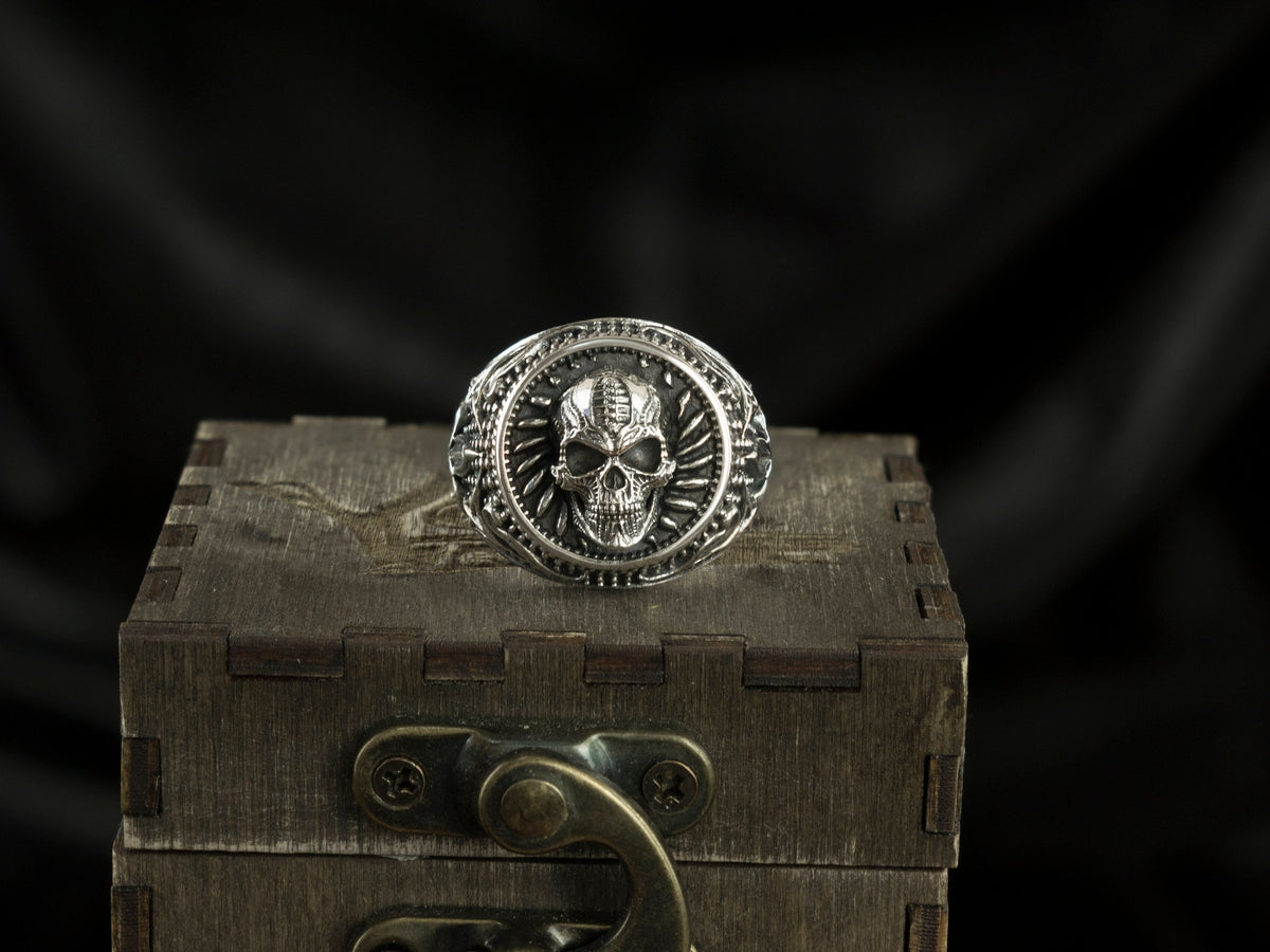 Blade Boss heavy sterling silver skull ring with circular relief on a wooden box