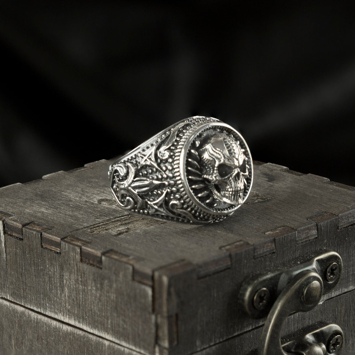 Heavy round skull signet ring on a wooden box, other angle