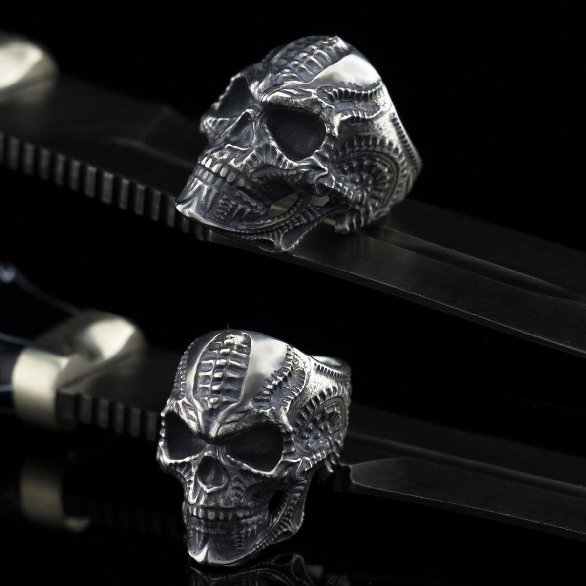 Blade skull ring resting on a black strap, angled view