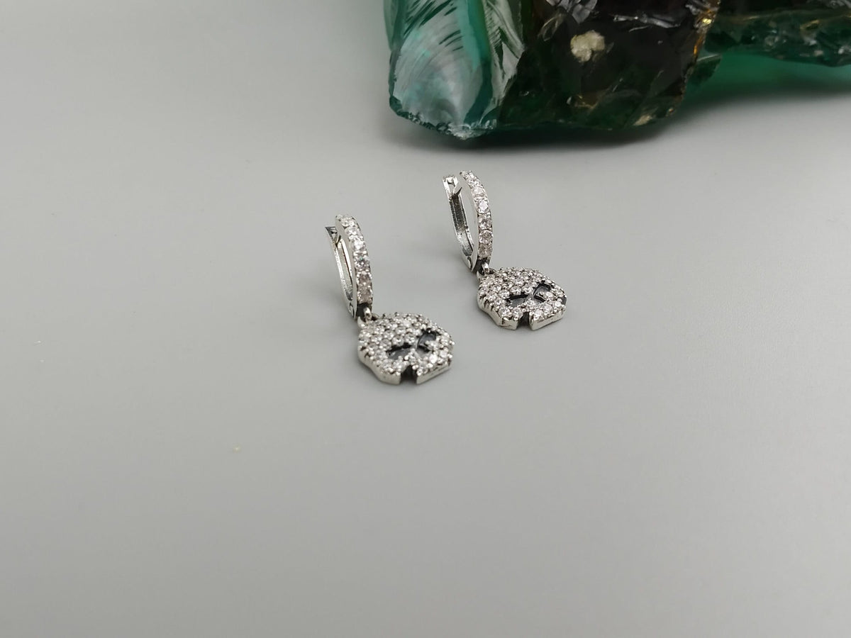 Crystal Skull CZ earrings at an angle on a gray background