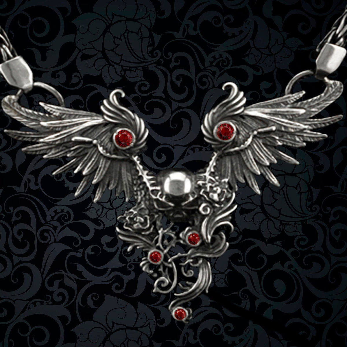 Close-up of Dark Angel necklace: feathered silver wings, central skull, roses and red cubic zirconia