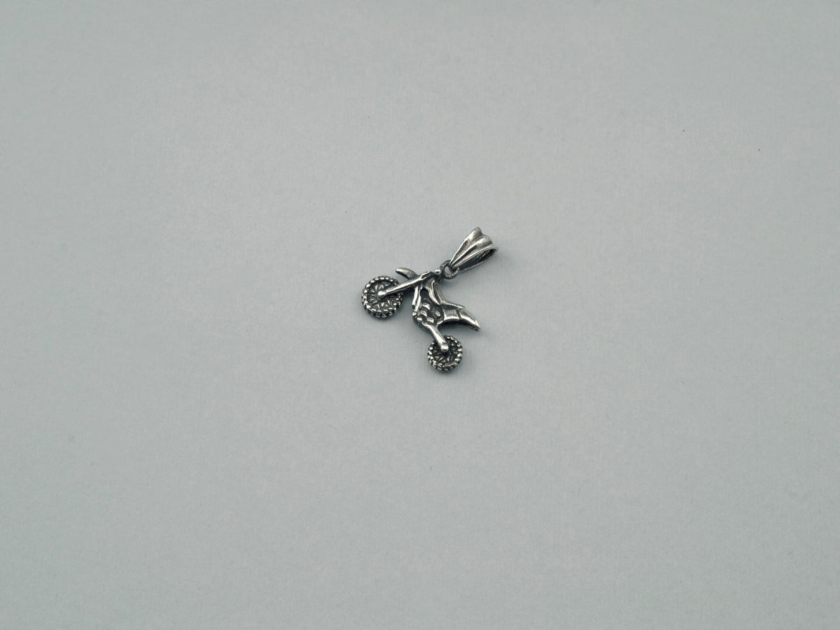 Side view of the silver enduro motorcycle pendant showing wheels and frame