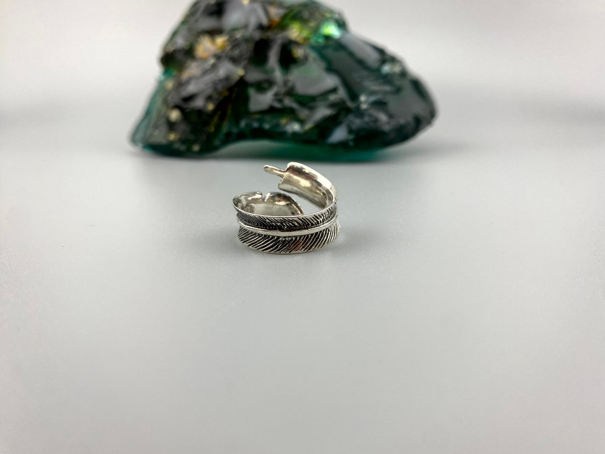 Adjustable feather ring lying on its side, textured feather detail