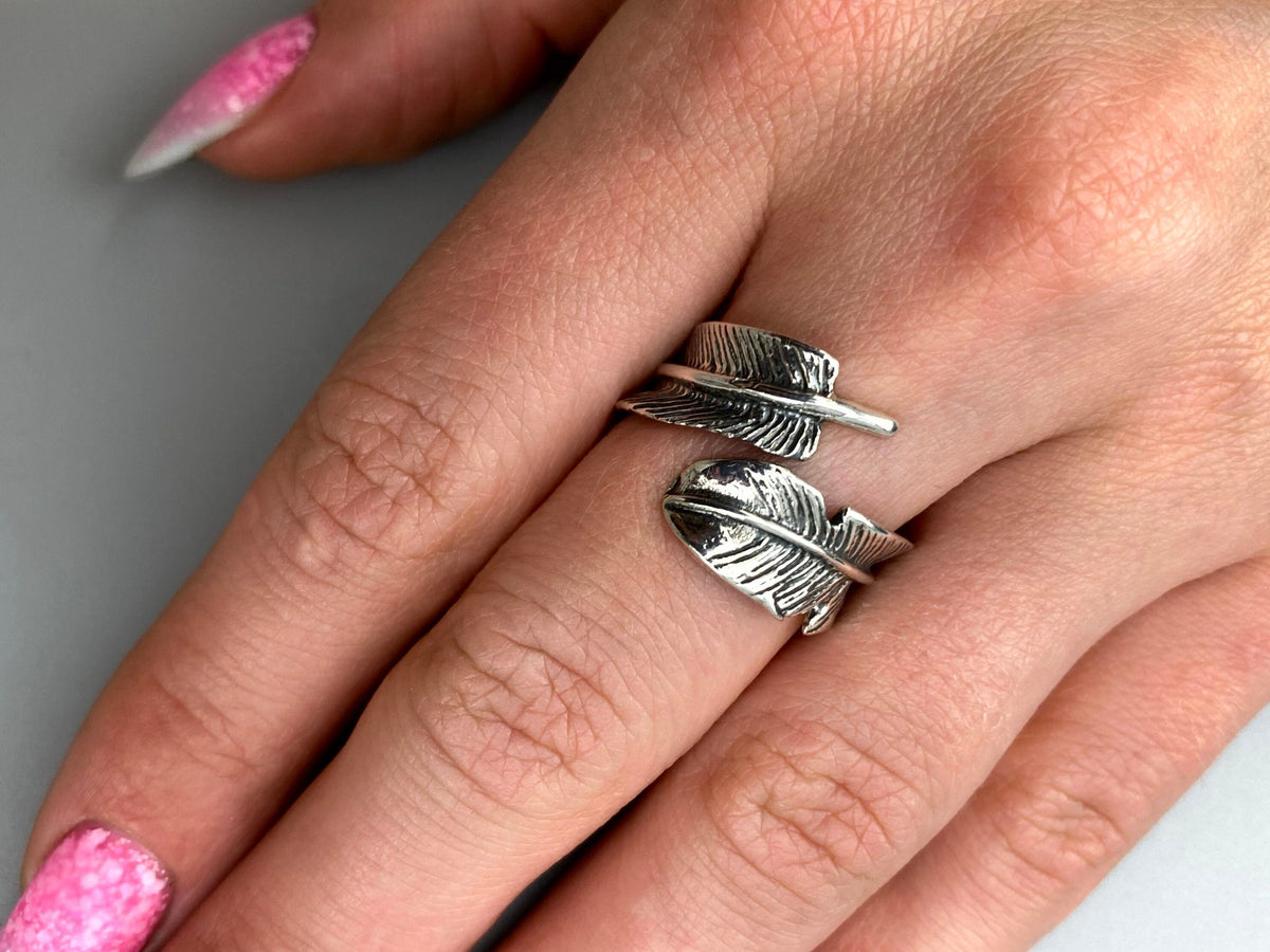 Feather adjustable sterling silver wrap ring worn on a woman's finger