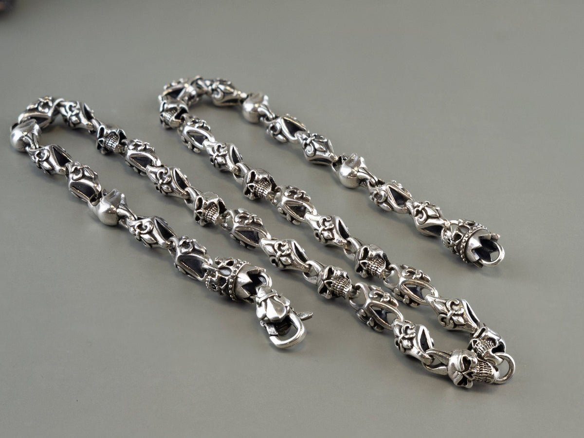 Fleur de lis crowned skull silver chain coiled with the clasp, on grey