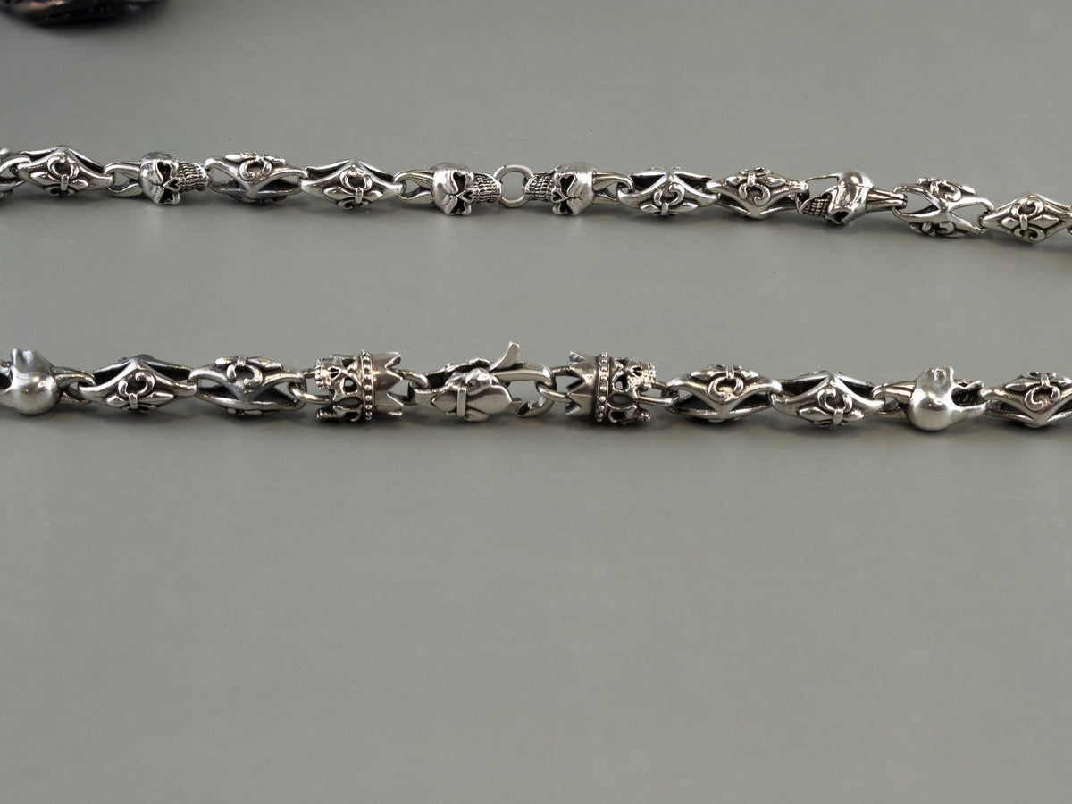 Close-up of the skull and fleur de lis links of the silver chain