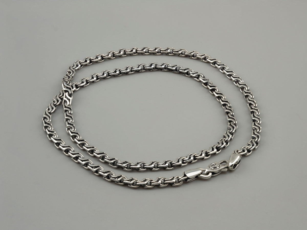Forge sterling silver chain laid flat in an oval, showing the lobster clasp