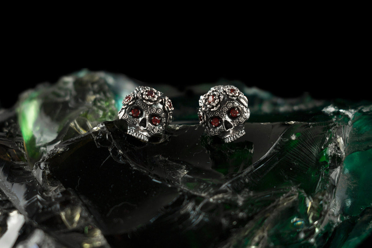 Frida skull stud earrings with red stones on green glass, wide view