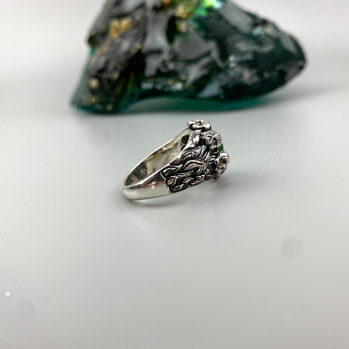 Women's silver skull ring lying on its side, skull detail