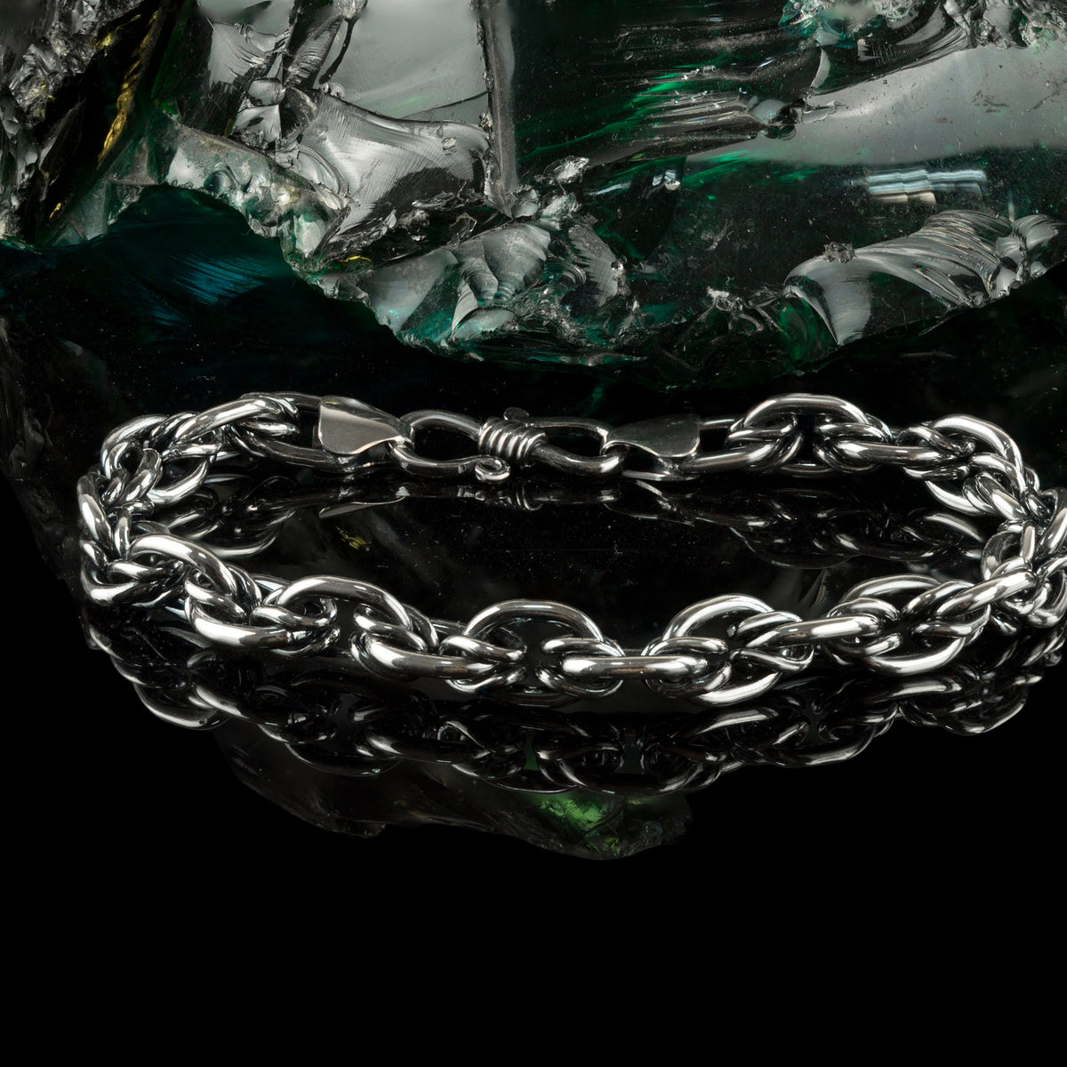 Graf silver bracelet resting on a dark rock, angled view