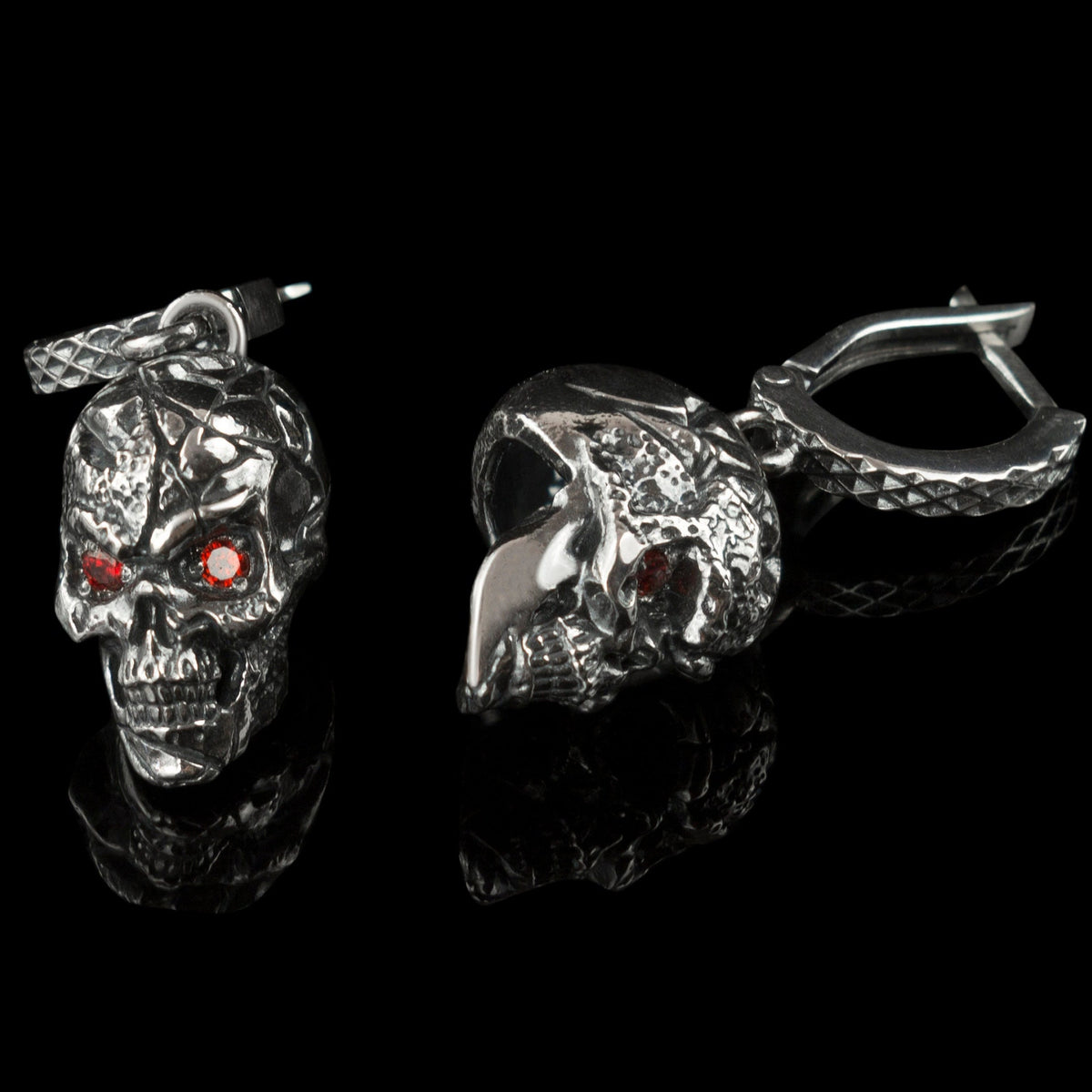 Headhunter earrings lying flat, cracked skull texture and red stones