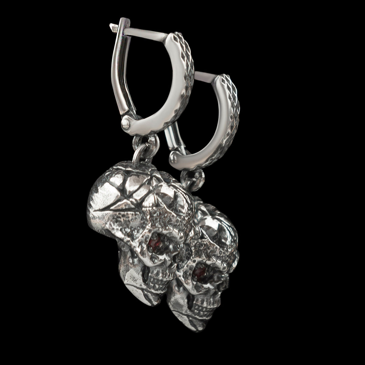 Close-up of a battle-worn silver skull earring hanging from its patterned hoop