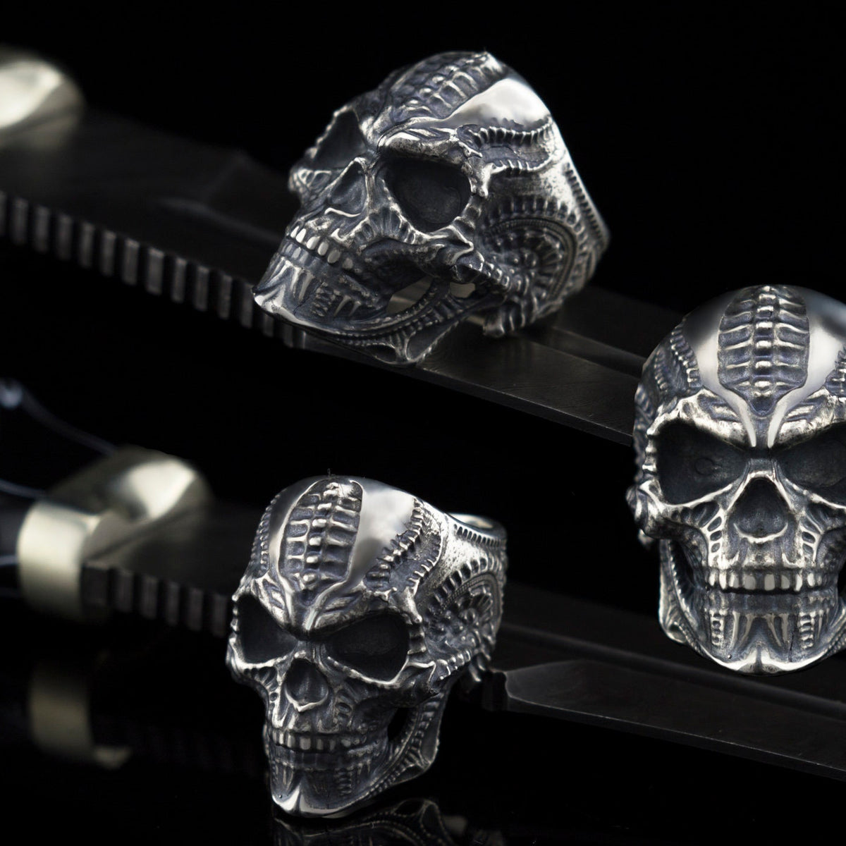 Biomechanical sterling silver skull ring shown from three angles on black background