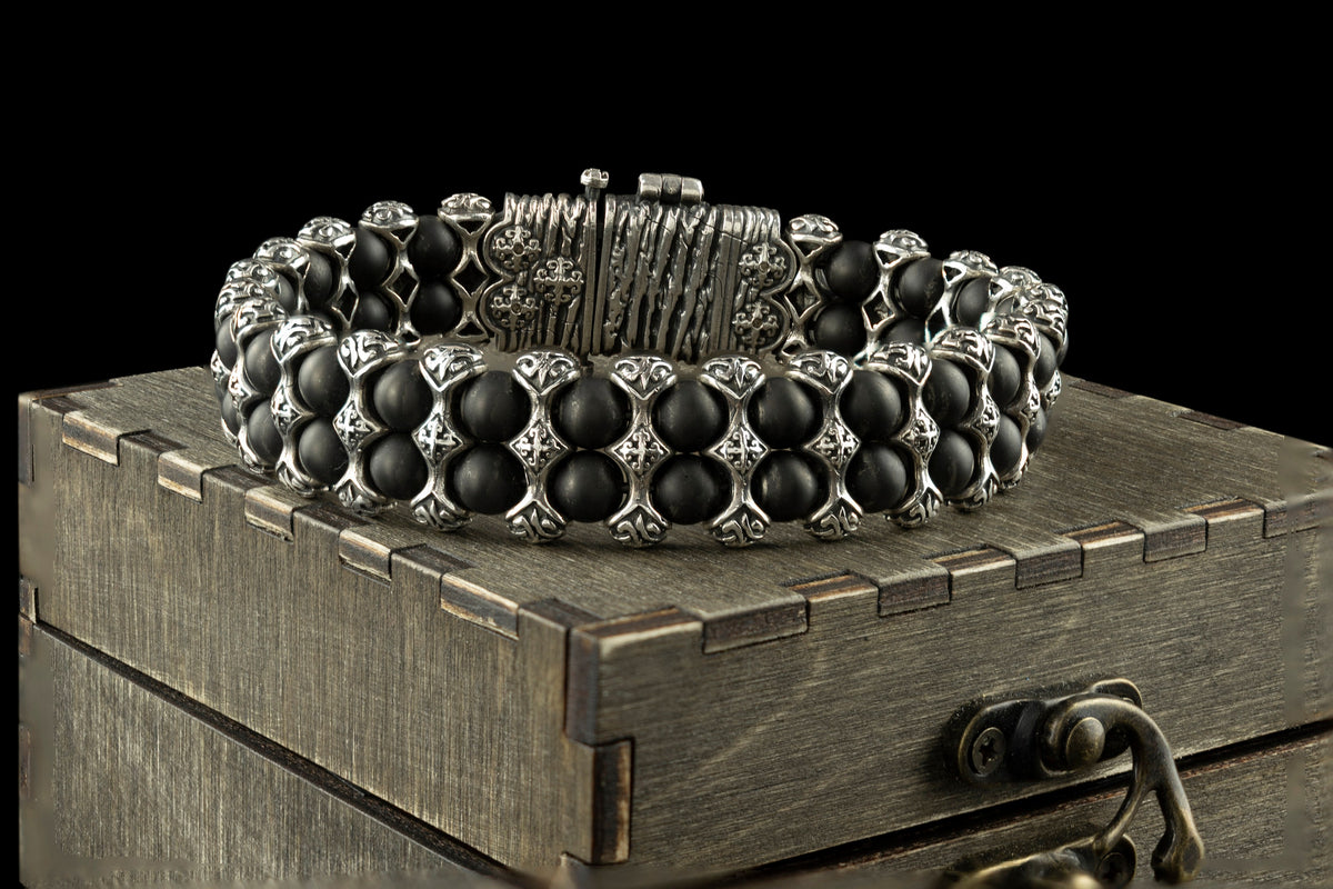 The Saint Victor bracelet by Yeti Jewelry features polished black onyx beads, intricately detailed sterling silver elements, and a prominent decorative central motif. This approximately 75-gram statement bracelet is handcrafted in 925 sterling silver and can be custom-made to the requested wrist size.