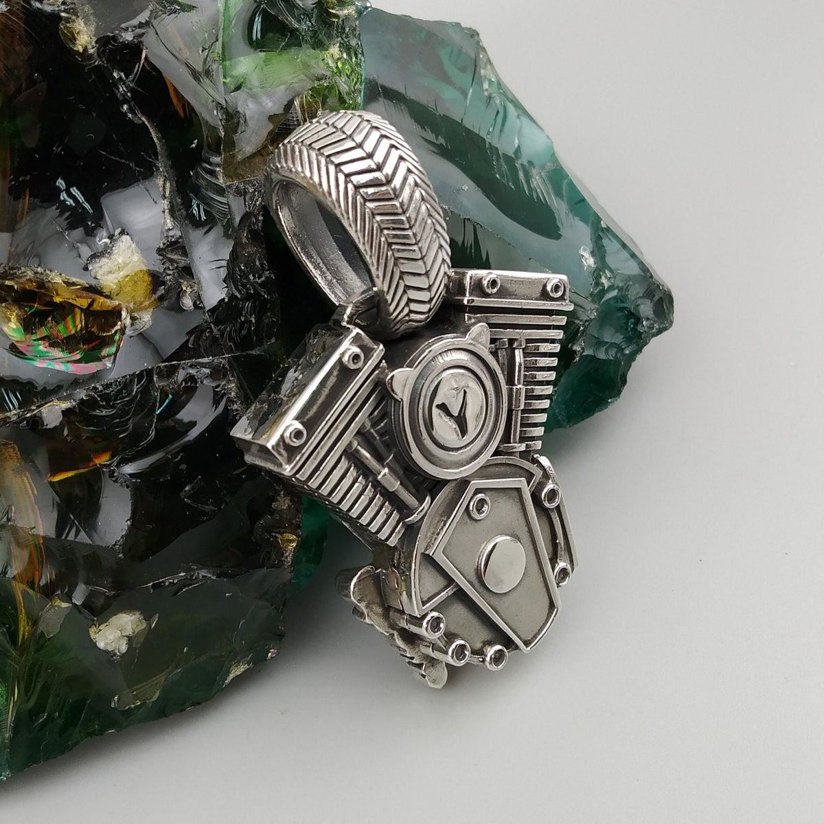 Vigor V-Twin skull pendant in 925 sterling silver with an ornamental fleur-de-lis-inspired emblem and sculpted mechanical details, photographed with a silver biker chain.