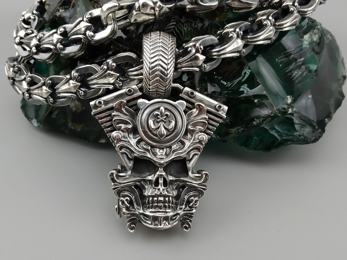 Vigor V-Twin skull pendant in 925 sterling silver with an ornamental fleur-de-lis-inspired emblem and sculpted mechanical details, photographed with a silver biker chain.