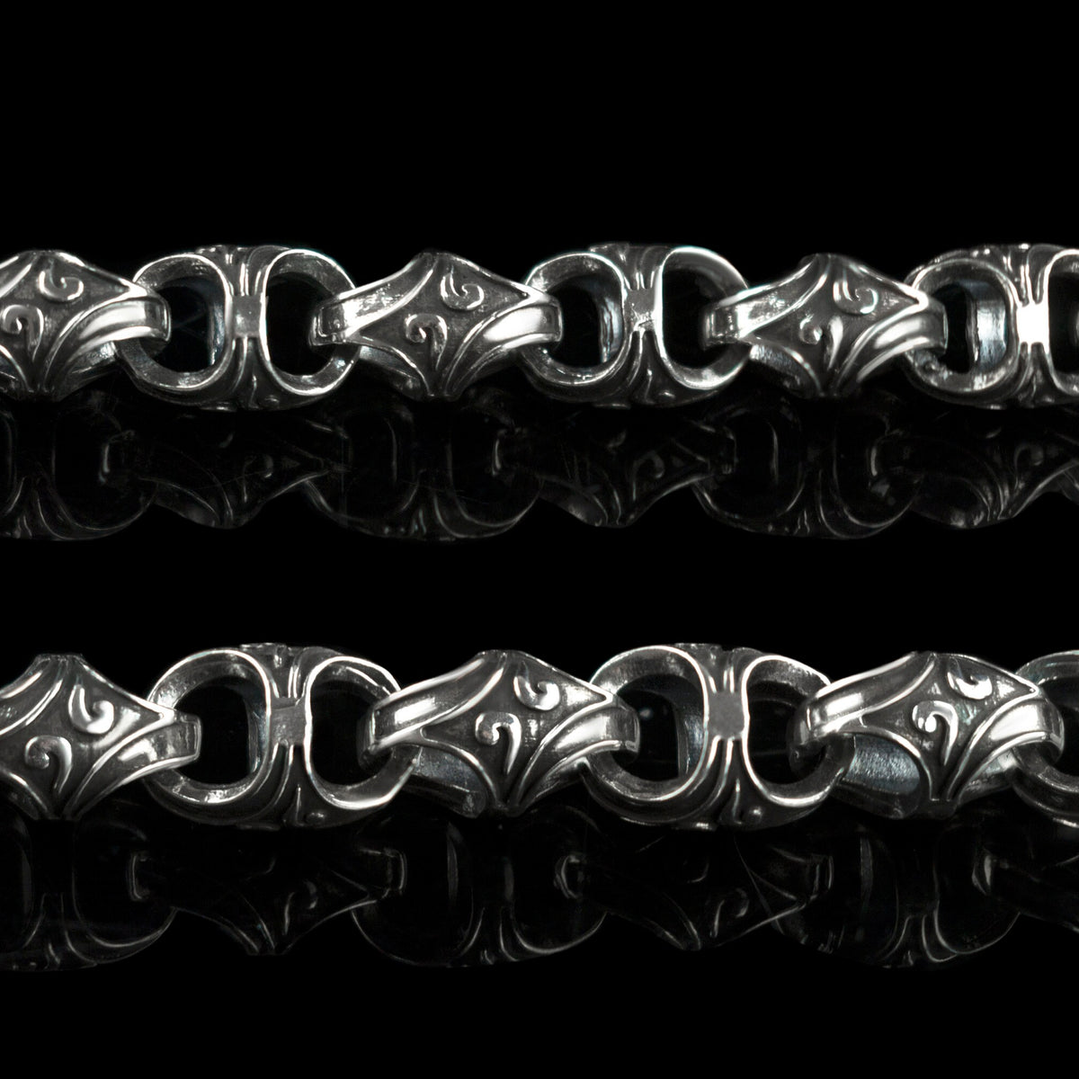 Close-up of Mokorr chain links with sculpted oxidized ornament and polished edges