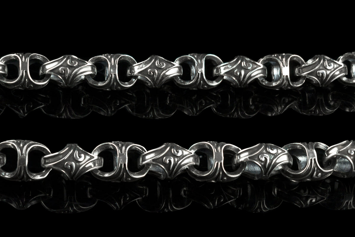 Close-up of Mokorr chain links with sculpted oxidized ornament and polished edges