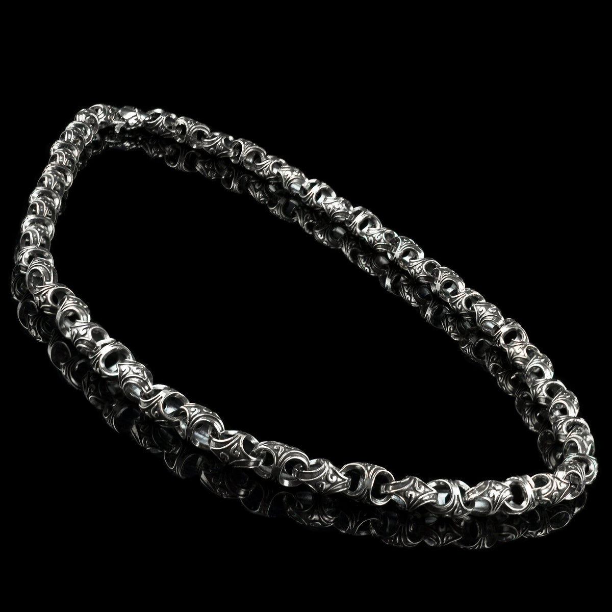 Heavy silver biker chain with ornate oxidized links, angled view on black