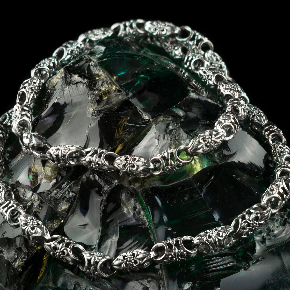 Ornate sterling silver chain draped in loops, showing oxidized link pattern