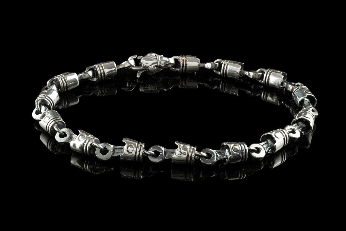 Full view of the piston and rod bracelet with lobster clasp on black background