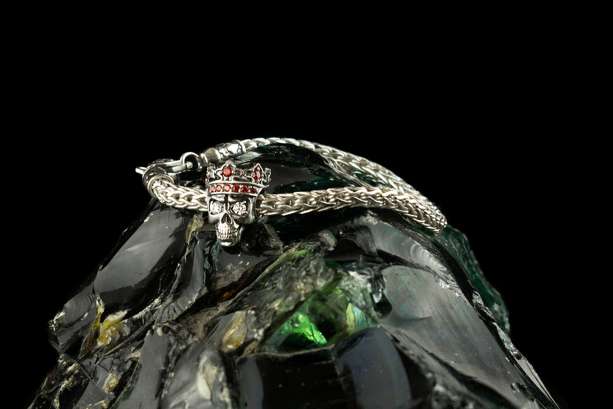 Santa Muerte skull charm on a silver chain bracelet, crown set with red stones