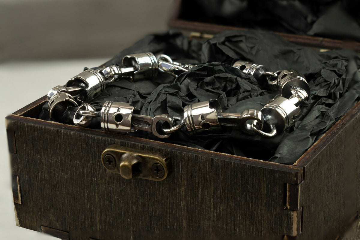 Heavy piston bracelet resting in an open box on black paper