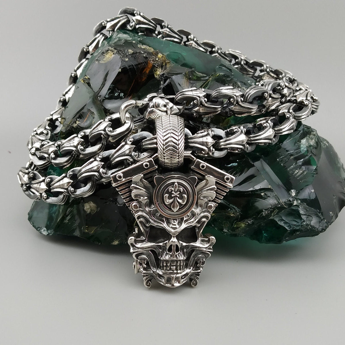 Vigor biker pendant lying on a heavy silver chain, top view