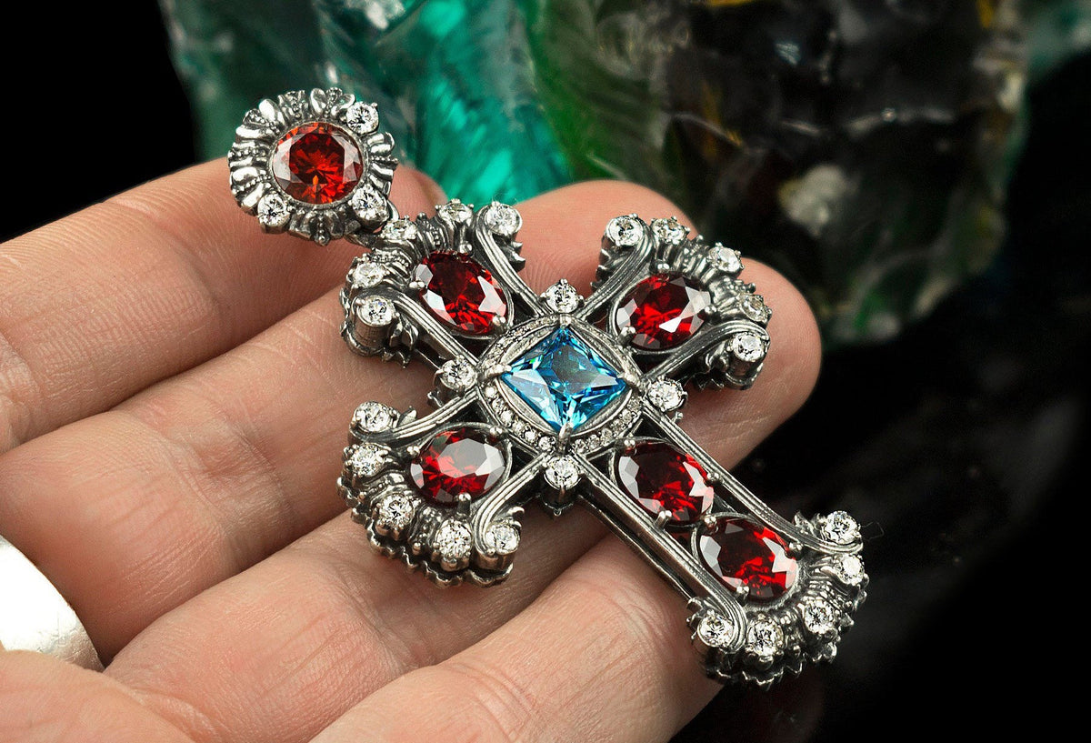 Ornate gothic cross pendant in 925 sterling silver with a blue cubic zirconia center and red CZ stones
