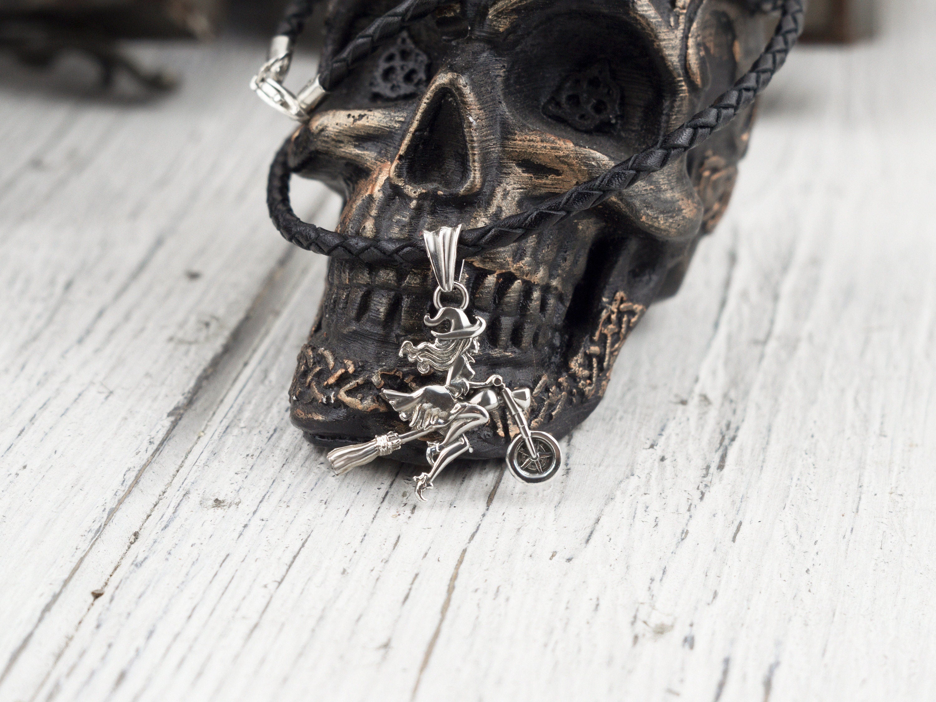 Allegra biker witch sterling silver pendant on a black cord against a dark skull