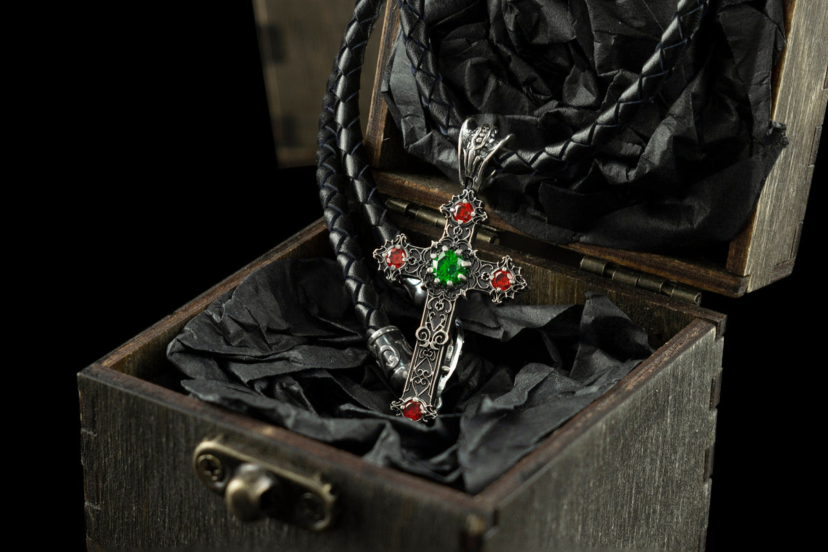 Aurora gothic cross pendant with green and red CZ on a leather cord in a wooden box