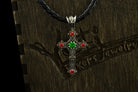 Aurora cross pendant with green center stone hanging in front of a logo gift box