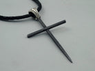 Close-up of the matte black spike cross pendant and polished ribbed bail on leather cord