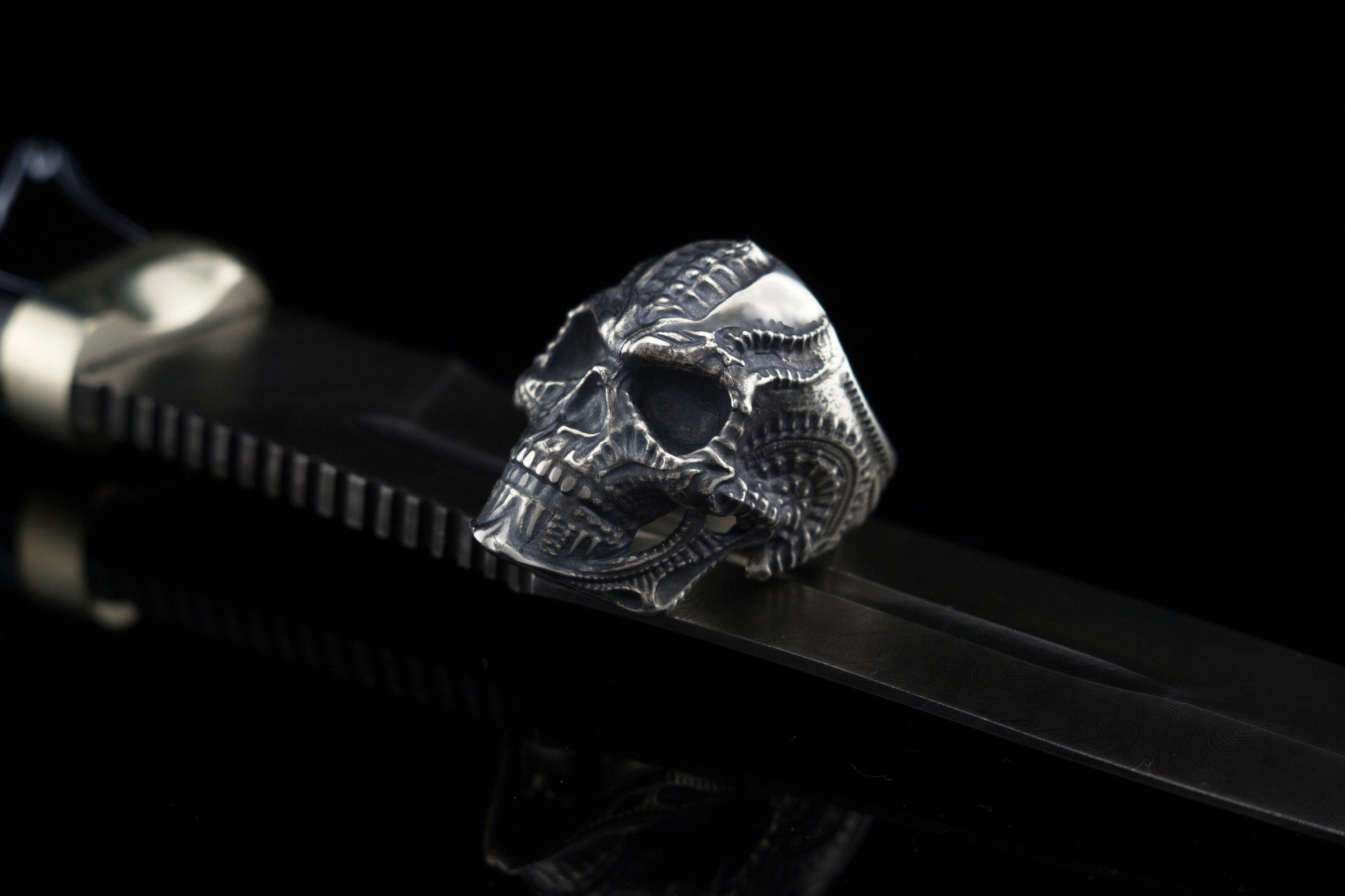 Blade skull ring on a black strap, ribbed biomechanical cranium