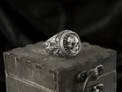 Heavy round skull signet ring on a wooden box, other angle
