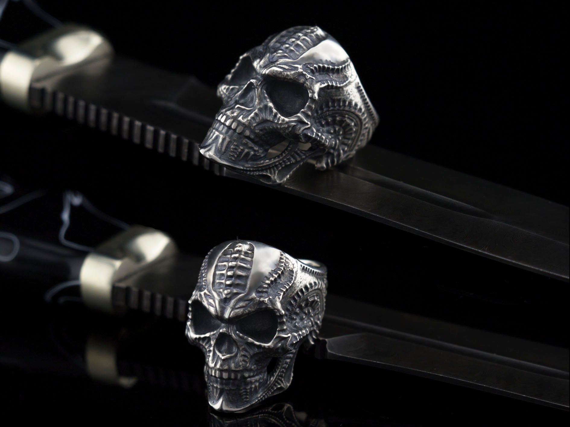 Blade skull ring resting on a black strap, angled view