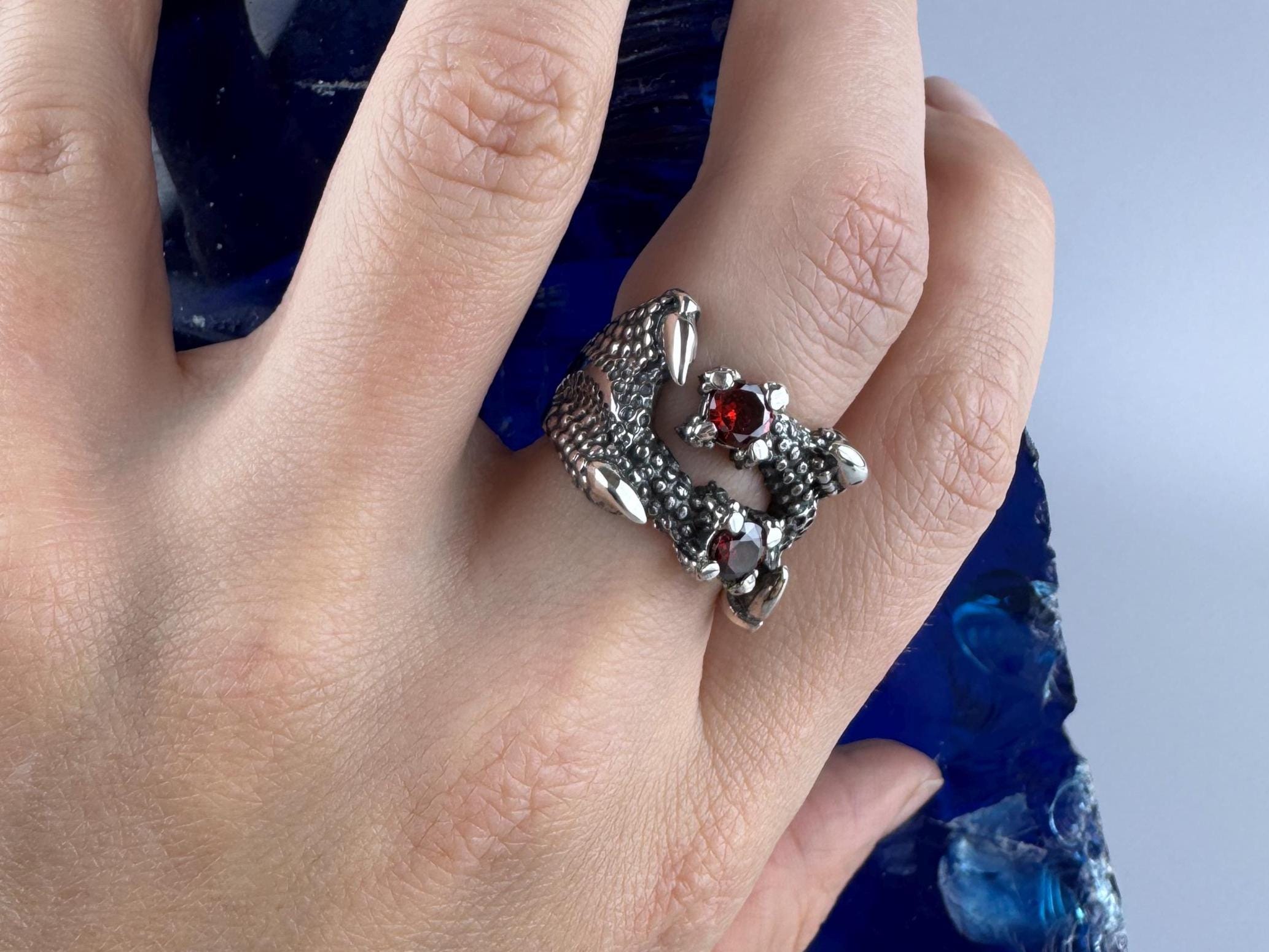 Silver dragon garnet ring worn on the finger, close-up hand view