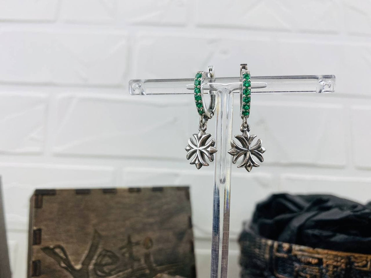 Front view of green CZ Maltese Cross earrings on a display stand