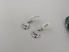 Pair of pave CZ skull drop earrings lying flat on a gray background