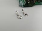 Crystal Skull CZ earrings at an angle on a gray background