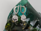 Front view of Crystal Skull CZ earrings on a green glass stone