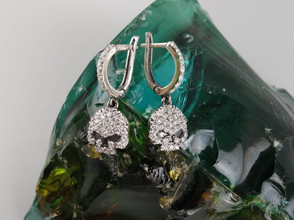 Front view of Crystal Skull CZ earrings on a green glass stone