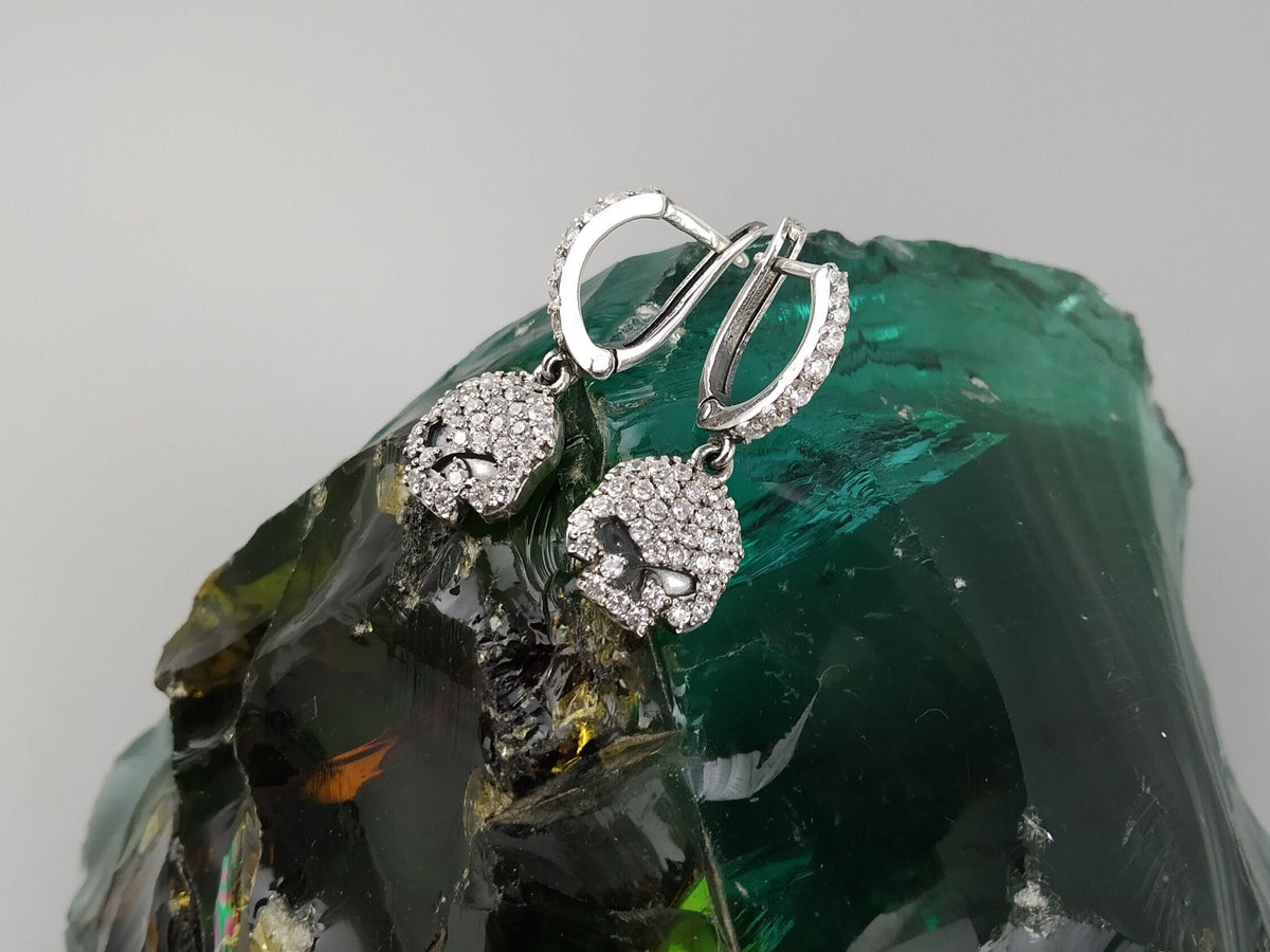 Crystal Skull earrings hanging on a green glass stone, side angle