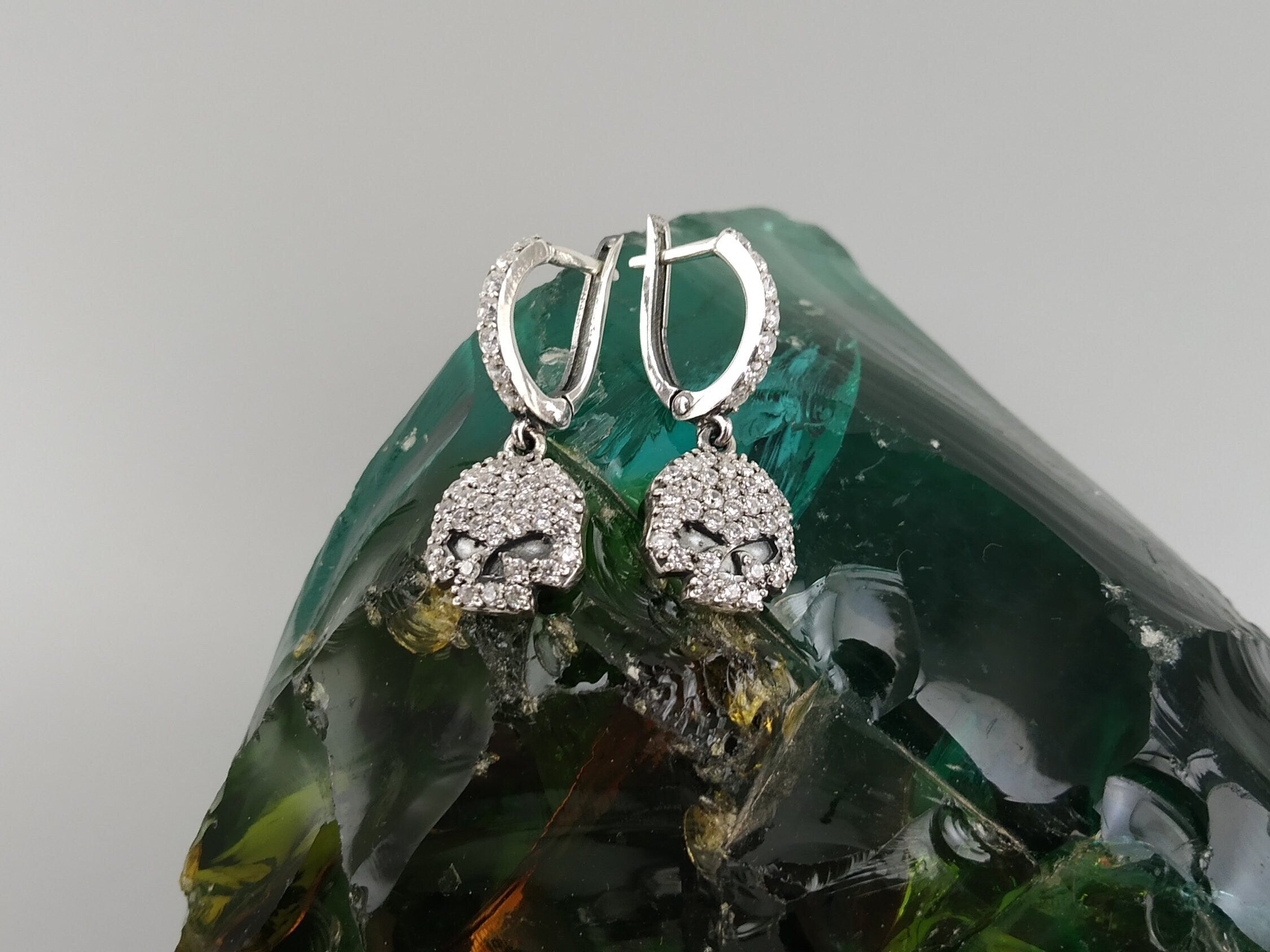Crystal Skull drop earrings standing upright on a green glass stone