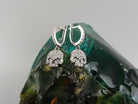 Crystal Skull drop earrings standing upright on a green glass stone