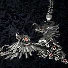 Angled view of the Dark Angel winged skull pendant with filigree and red stones on woven chain