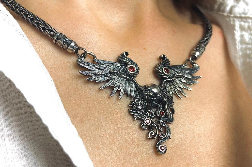 Dark Angel sterling silver winged skull necklace with red stones worn on the neck